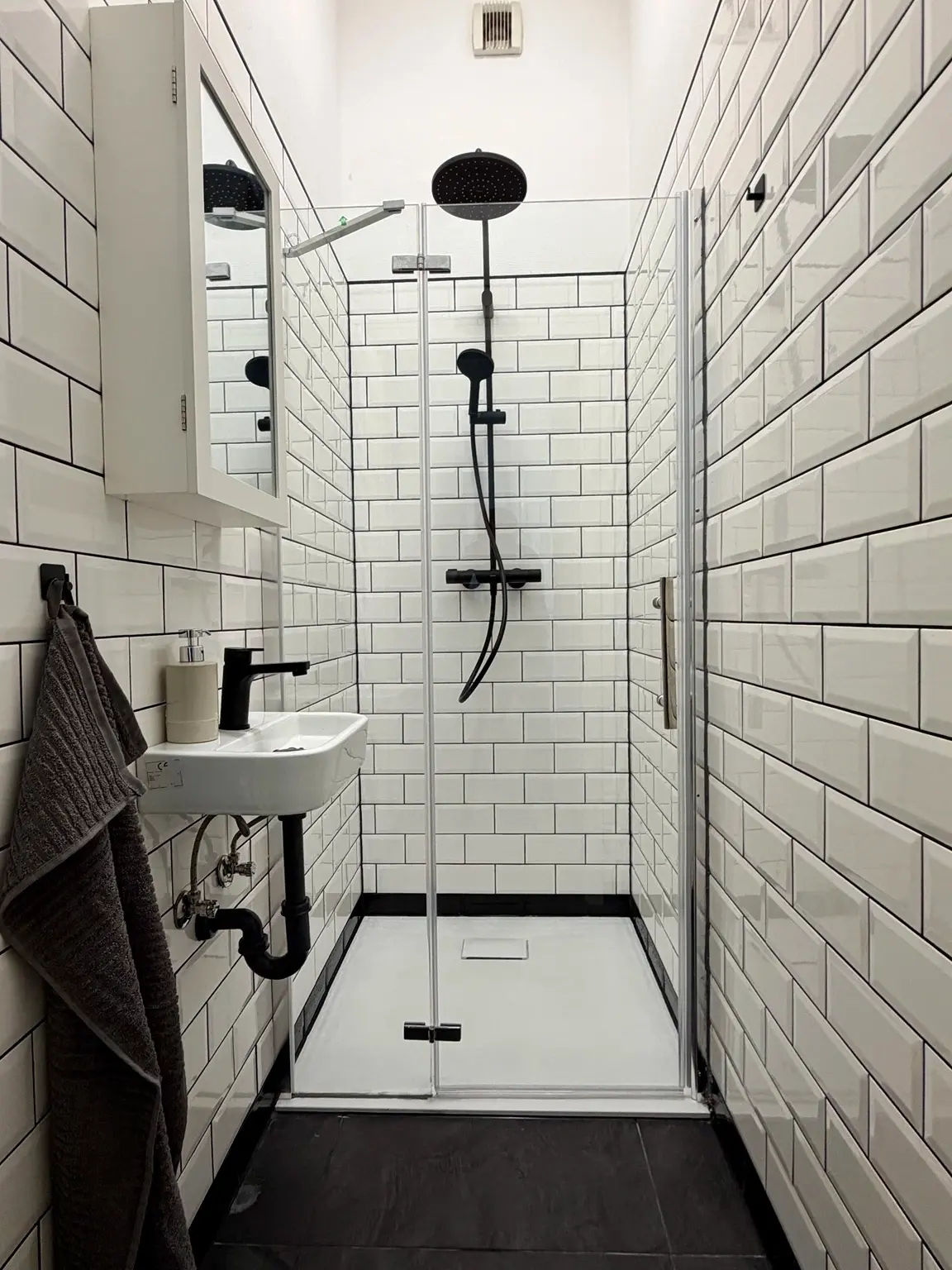 Moderne Dusche mit weißen Fliesen und schwarzen Armaturen