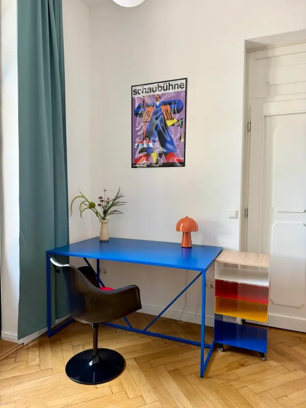 Second workspace with a blue desk, leather chair and Bauhaus poster