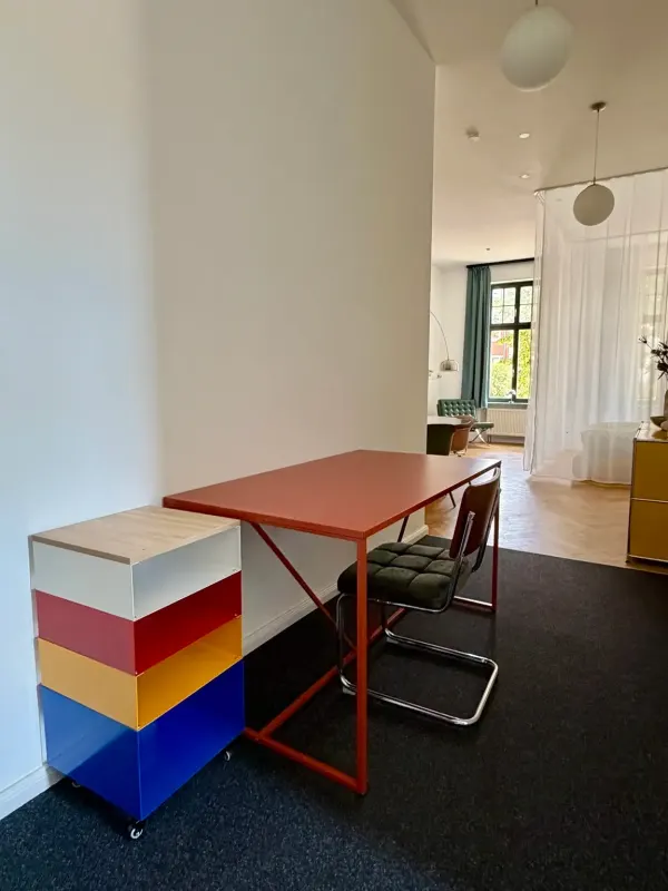 Workspace with a red desk, cantilever chair and drawer unit in Bauhaus colours
