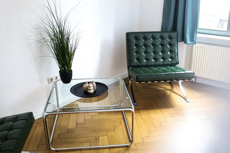 Green Barcelona chair and chrome glass table by the window of the holiday apartment