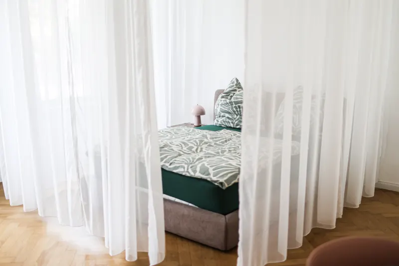 Double bed behind blackout curtains in the separated sleeping area of the Bauhaus Suite