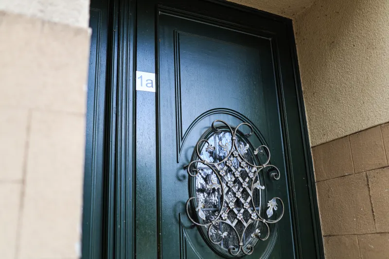 Dark green front door of number 1a with a wrought-iron Art Nouveau grille