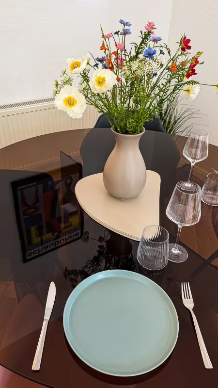 Close-up of the table setting with a turquoise plate, wine glasses and a bunch of wild flowers