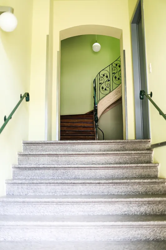 Bright stairwell of the villa with granite steps, green walls and a curved handrail